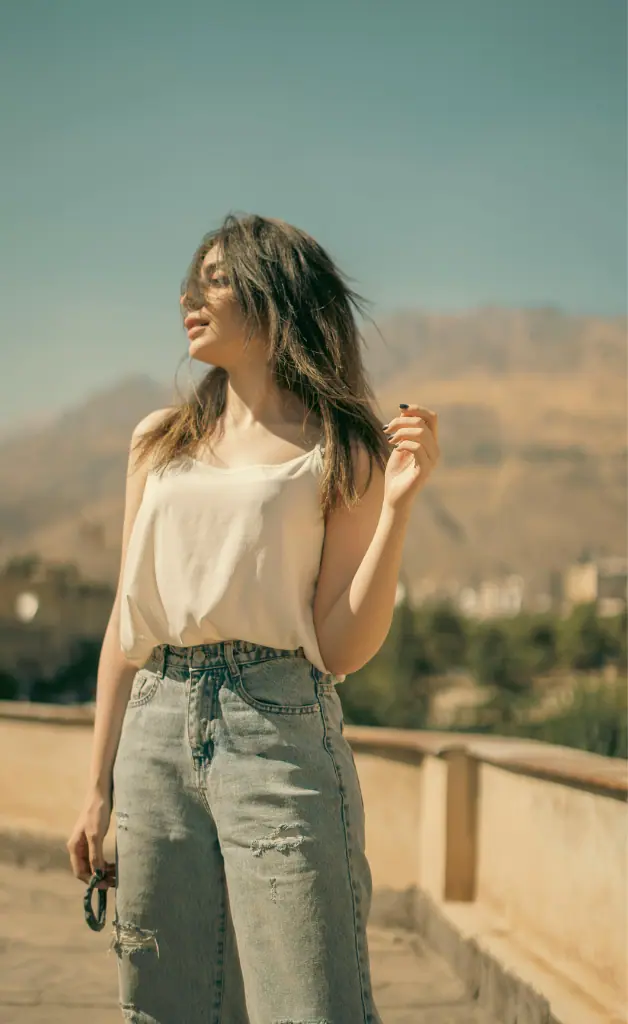 A girl wearing a white shirt and jeans is looking to the side